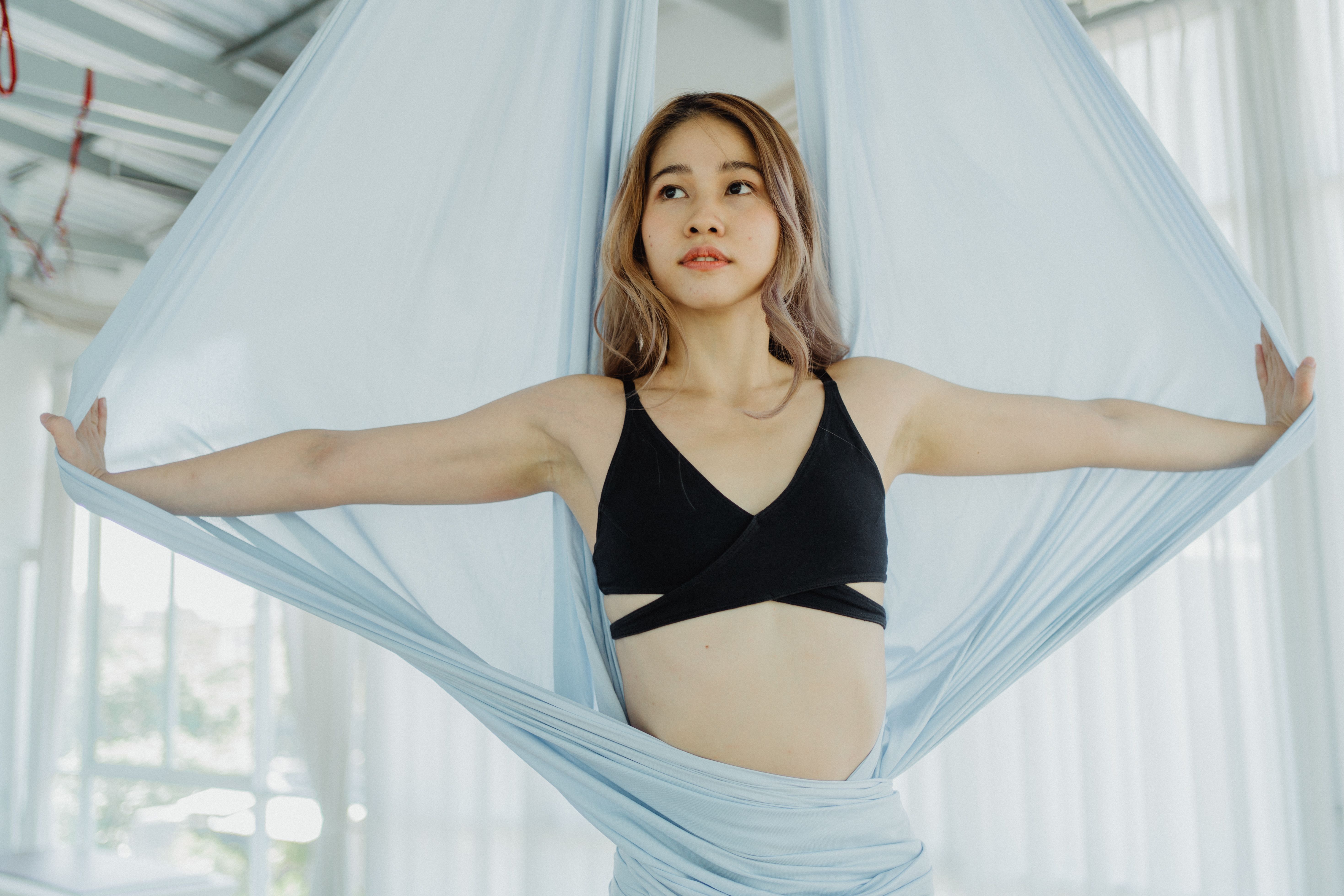一名妇女在室内用丝绸表演空中瑜伽，强调健身和正念