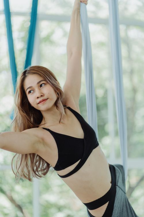 Free Young woman practicing aerial yoga indoors, showcasing strength and balance. Stock Photo