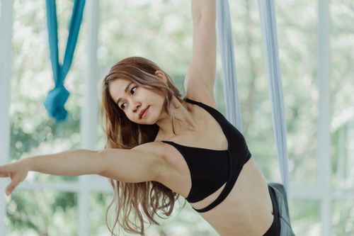 Free Close-up of an Asian woman practicing aerial yoga indoors, showcasing fitness and flexibility. Stock Photo