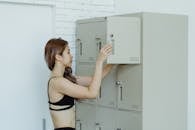 Woman in Black Brassiere and Panty Standing Beside Gray Cabinet