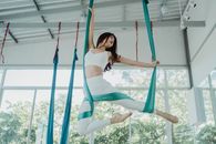 Woman in Teal Tank Top and White Pants Jumping on Blue and White Rope