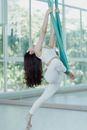 Woman in White Tank Top and White Pants Bending Her Body by the Window