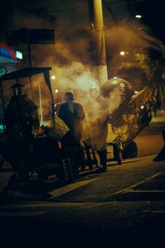 繁华的夜景中，一个热闹的街头食品供应商在烟雾笼罩的地区忙碌着