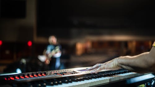 Unrecognizable person playing song on digital piano on stage during music show in concert hall