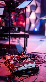 Modern pedalboard with wires placed on stage under colorful illumination during music show