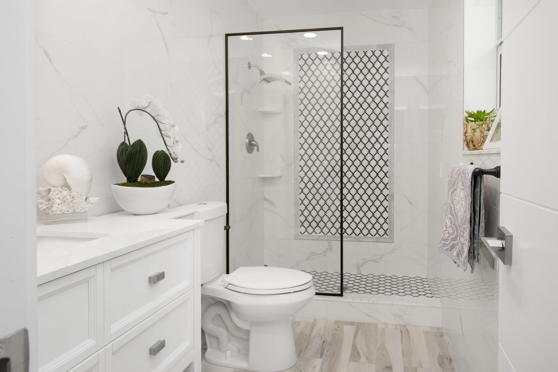 Elegant white bathroom with simple glass shower and restrained contemporary decor