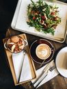 Top view arrangement of healthy bowl with porridge placed near plate with tasty salad and cup of hot coffee with cutlery on table