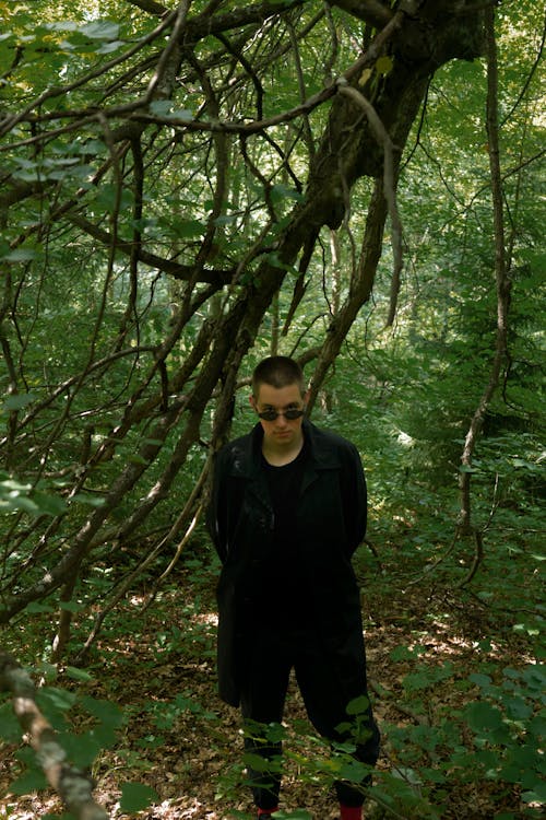 Trendy man in black apparel walking in forest