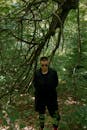 Trendy man in black apparel walking in forest