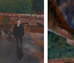 Stylish dreamy man reflecting in icy pond behind brick fence