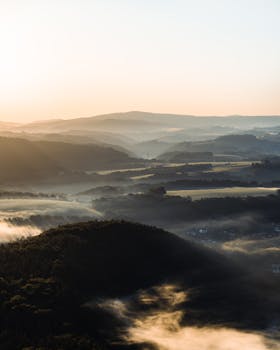 A breathtaking aerial view of a misty mountain landscape during sunrise, capturing serene natural beauty.