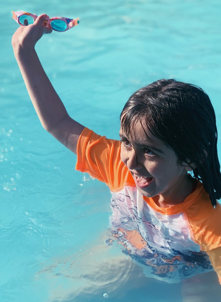 Happy Child With Goggles In Swimming Pool