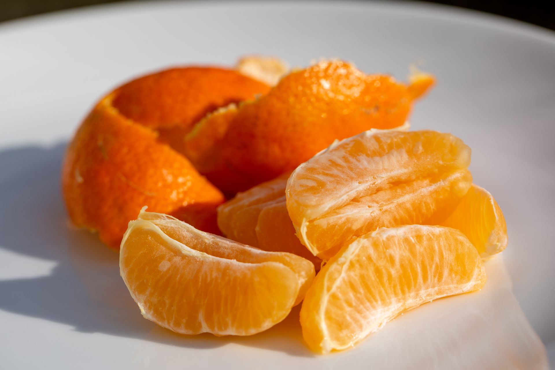 Close-up of peeled and sliced orange segments on a white plate, showcasing vibrant freshness.