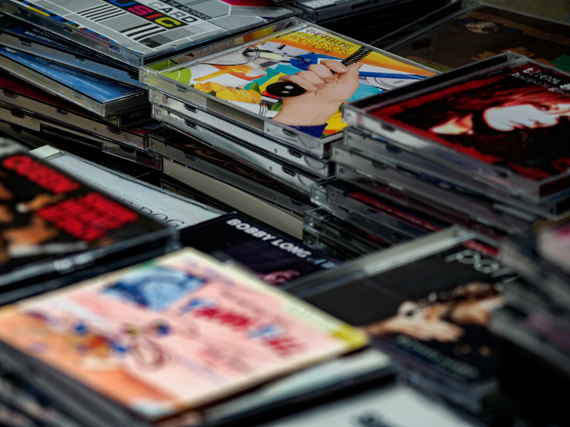 Close-up of a vibrant assortment of music CDs in plastic cases, showcasing various album covers.