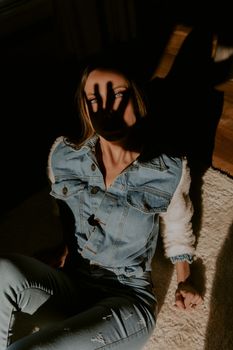 白天，一位穿着牛仔布的时尚女性在室内开玩笑地投下阴影