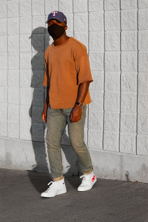 Man Wearing Brown T-shirt Standing Beside Wall