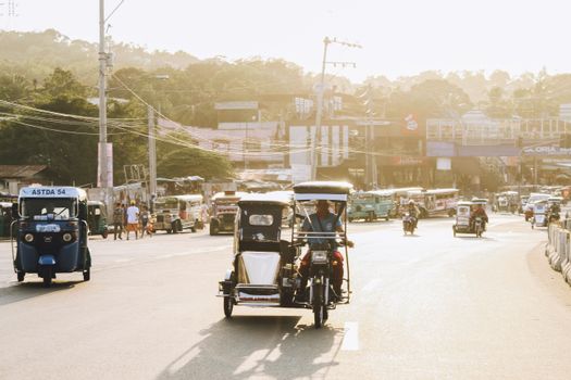 Sunlit street scene with tricycles in the Philippines, showcasing local transportation.