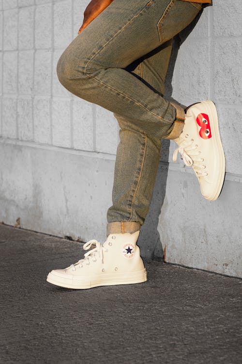 Person Wearing White Converse Sneakers Standing Against a Wall