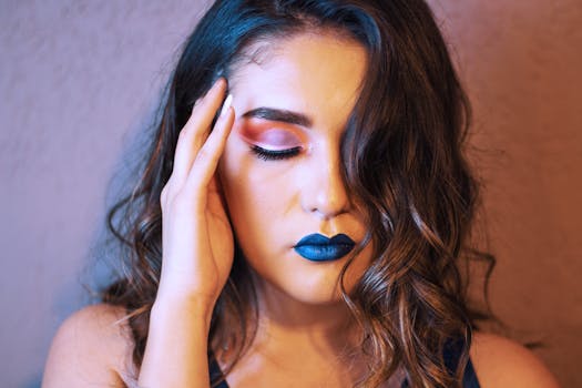 A striking portrait of a Hispanic woman with bold makeup and curled hair, eyes closed.