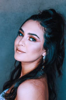 Stunning portrait of a woman with creative makeup and elegant earrings, showcasing fashionable style in a studio setting.