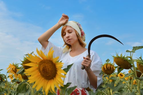 Tired woman with scythe working in field