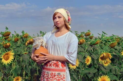 Wistful woman standing among blooming sunflowers