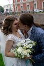 Unrecognizable groom biting nose of smiling bride on street
