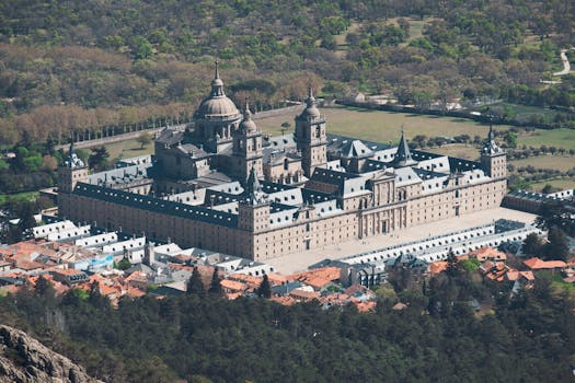 Stunning aerial view of El Escorial Monastery surrounded by lush greenery and architectural beauty.