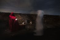 墓地的神秘夜色中，有一个幽灵和一个穿红色斗篷的人