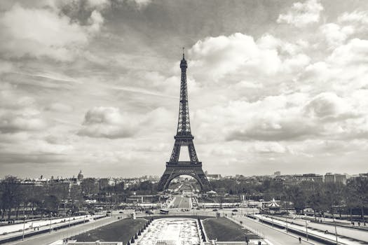 Monochrome photo of Eiffel Tower against a cloudy sky, Paris landmark.