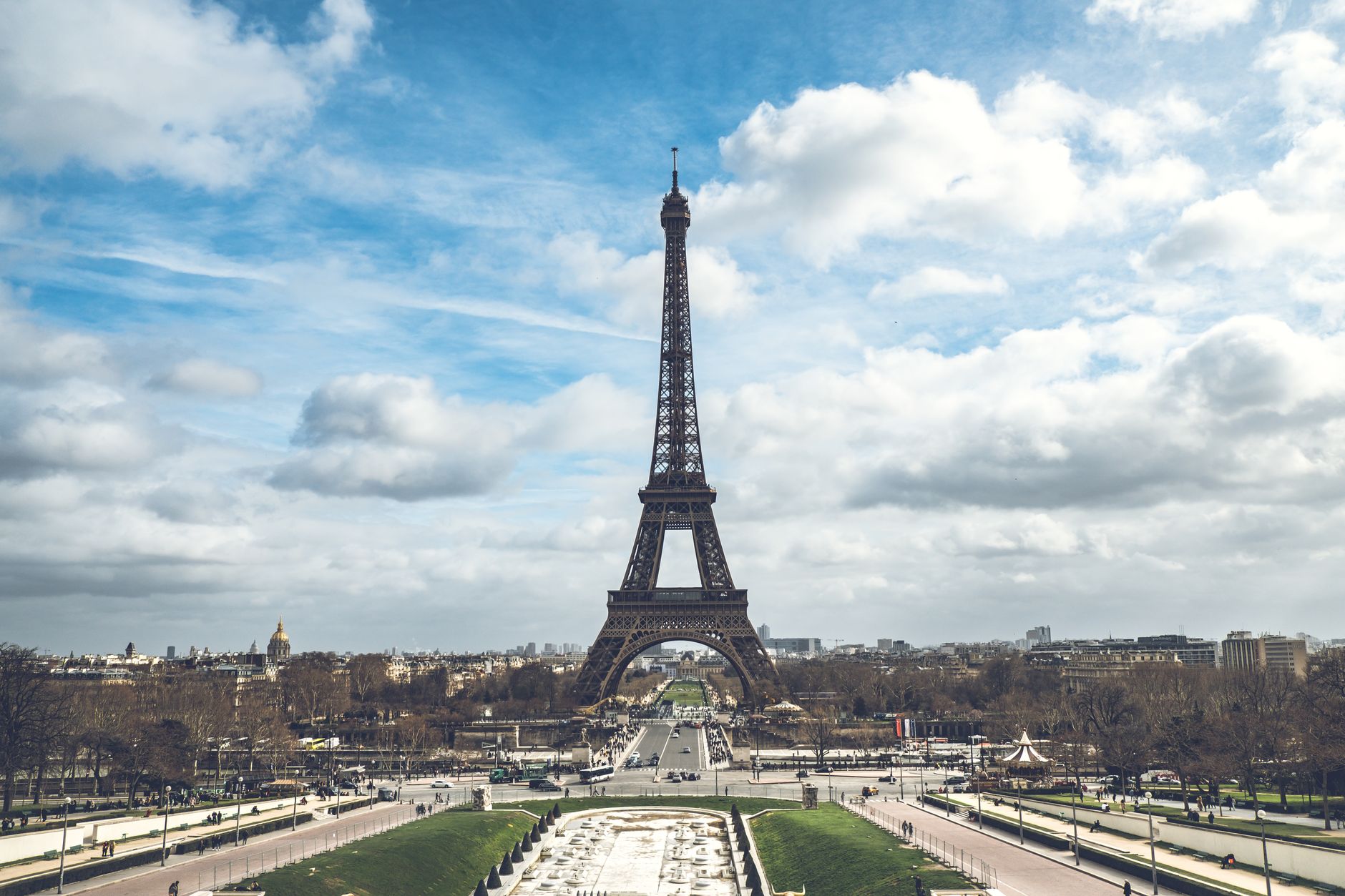Iconic view of the Eiffel Tower in Paris under a vibrant cloudy sky.
