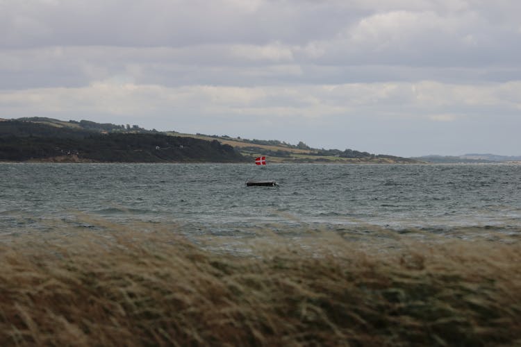 A Floating Barge On Water Near Green Grass