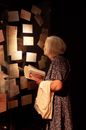 Anonymous elderly woman standing near showpieces in museum