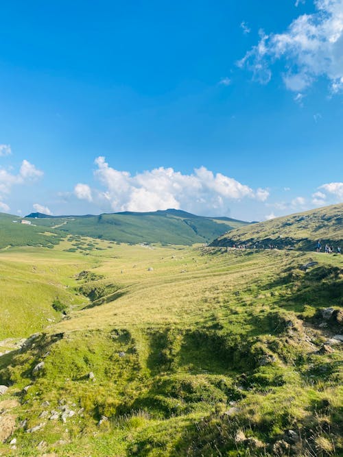 Green Grass Field and Hills Under Blue Sky