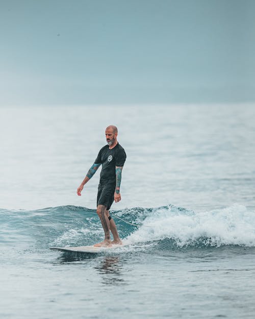 Man in Black Wet Suit Surfing on Sea