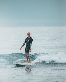 A surfer with tattoos skillfully maneuvers waves on a calm ocean in a serene setting.