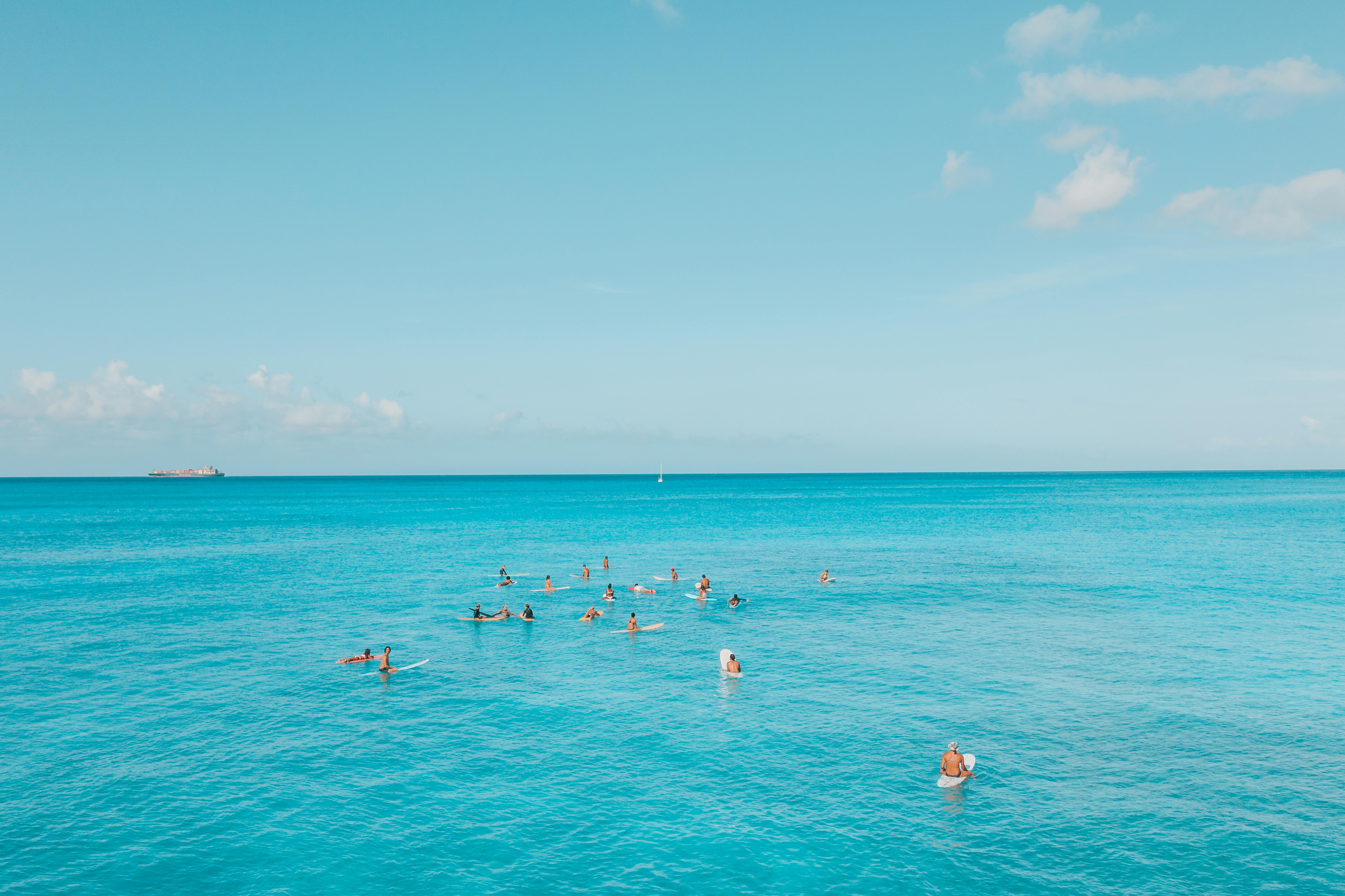 在夏威夷，一群冲浪者正享受着清澈的蓝色海洋和晴朗的天空，这完美的热带天堂场景