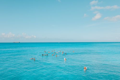 Free A group of surfers enjoying the clear blue ocean and sunny skies in Hawaii. Perfect tropical paradise scene. Stock Photo