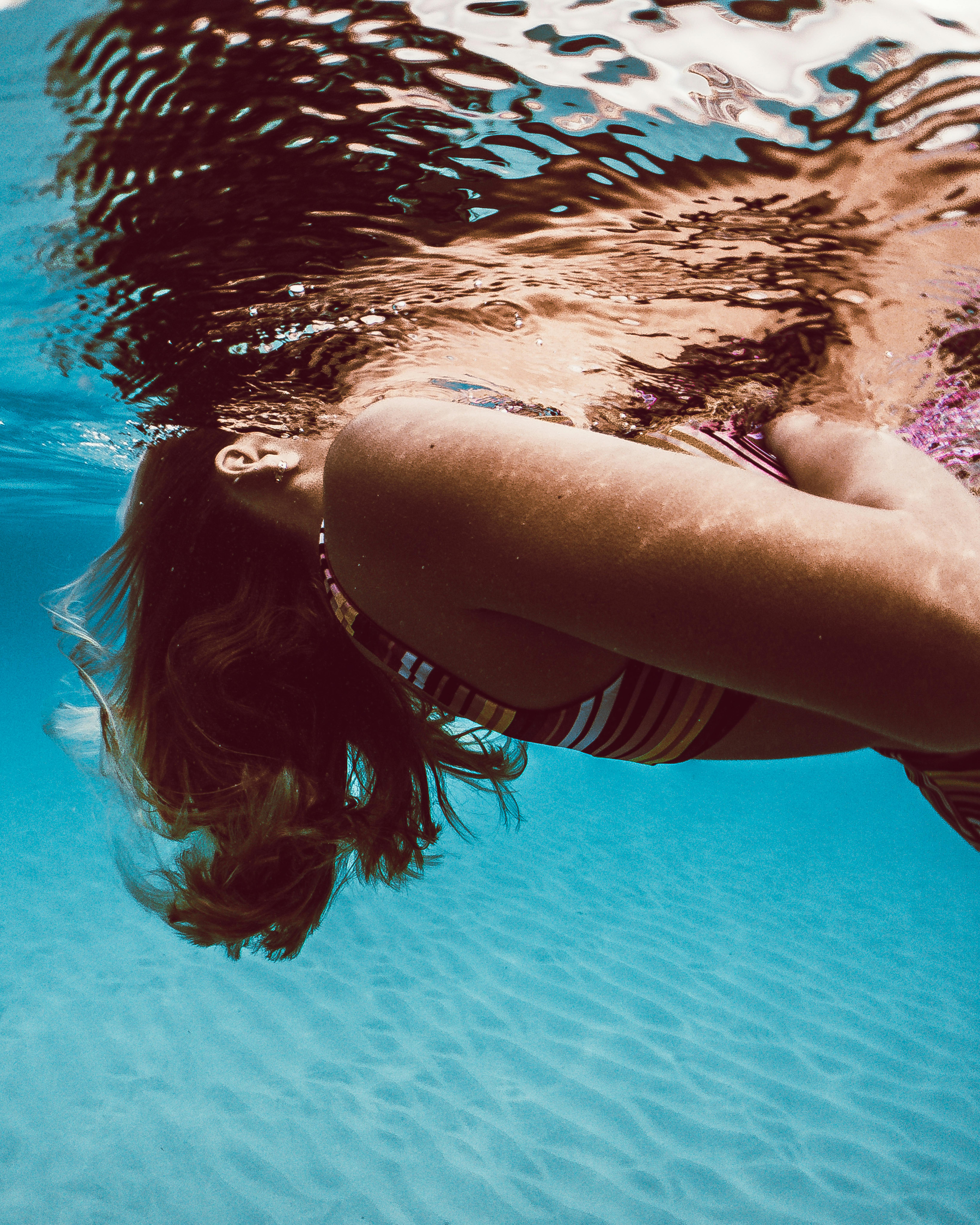 A serene moment captured of a woman swimming underwater in the clear Hawaiian ocean, showcasing tranquility and beauty.