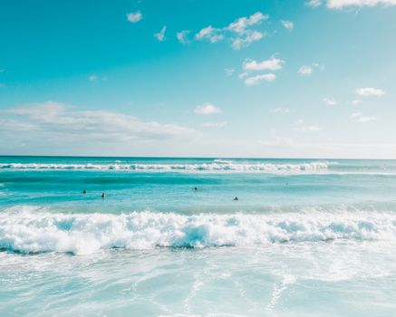 High waves and surfers in the turquoise ocean of Hawaii, capturing the essence of island life.