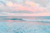 日落时分，冲浪者在柔和的天空下冲浪