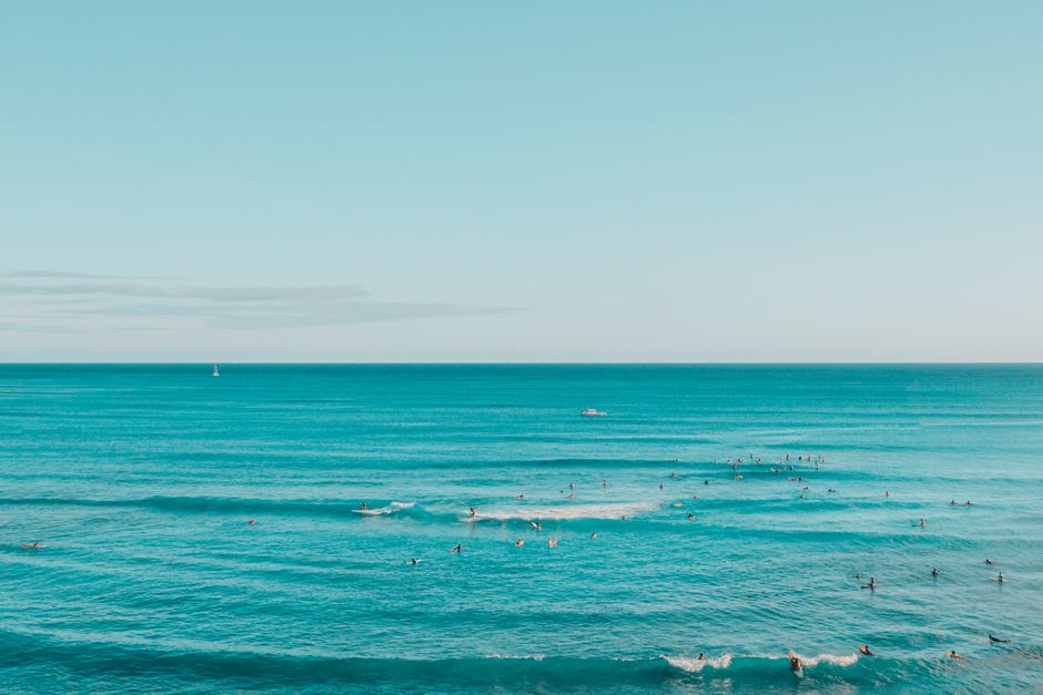 Surfers catching waves under a bright blue sky in Hawaii, showcasing island life.