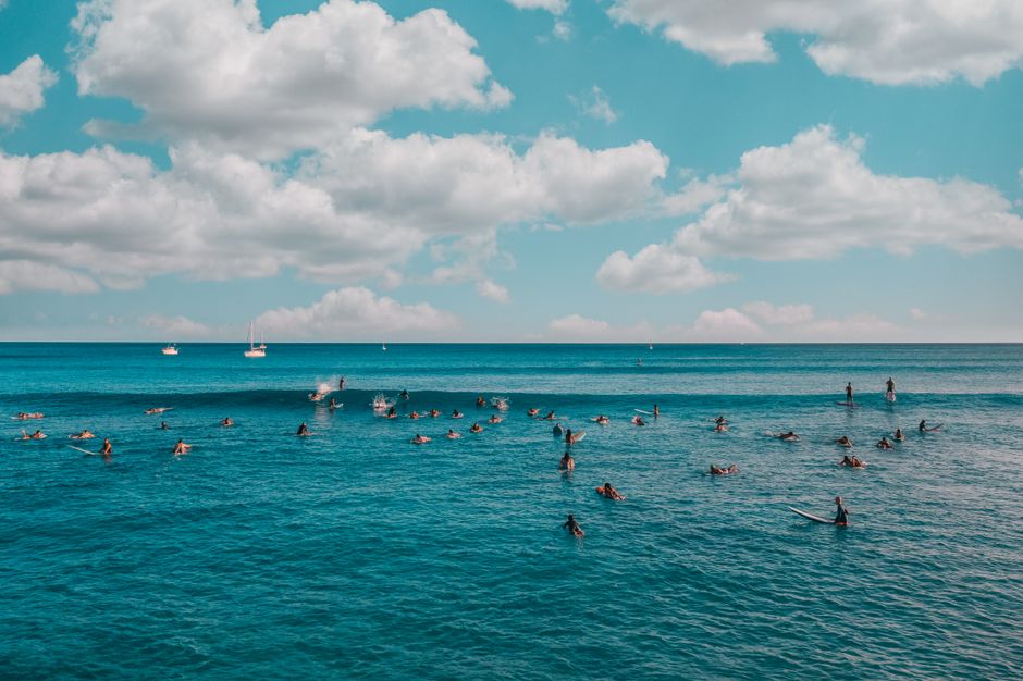 Surfing enthusiasts enjoy the waves under a bright blue sky in Hawaii's beautiful ocean.