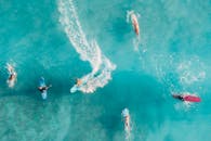 无人机镜头捕捉冲浪者享受充满活力的碧绿海浪，展示动态的水上运动动作