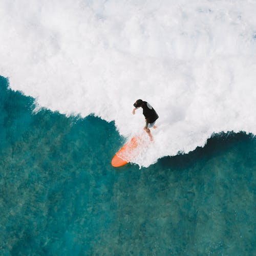 Person in Black Long Sleeves Doing Surfing on Water Waves