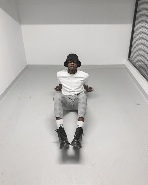 Man in White Shirt and Gray Pants Sitting on Gray Floor