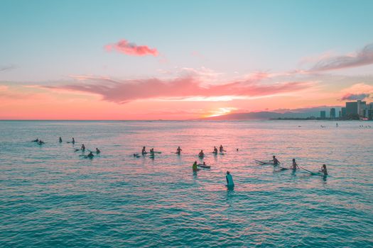 冲浪者在地平线上色彩缤纷的日落中，享受着充满活力的海洋与轻松的热带氛围