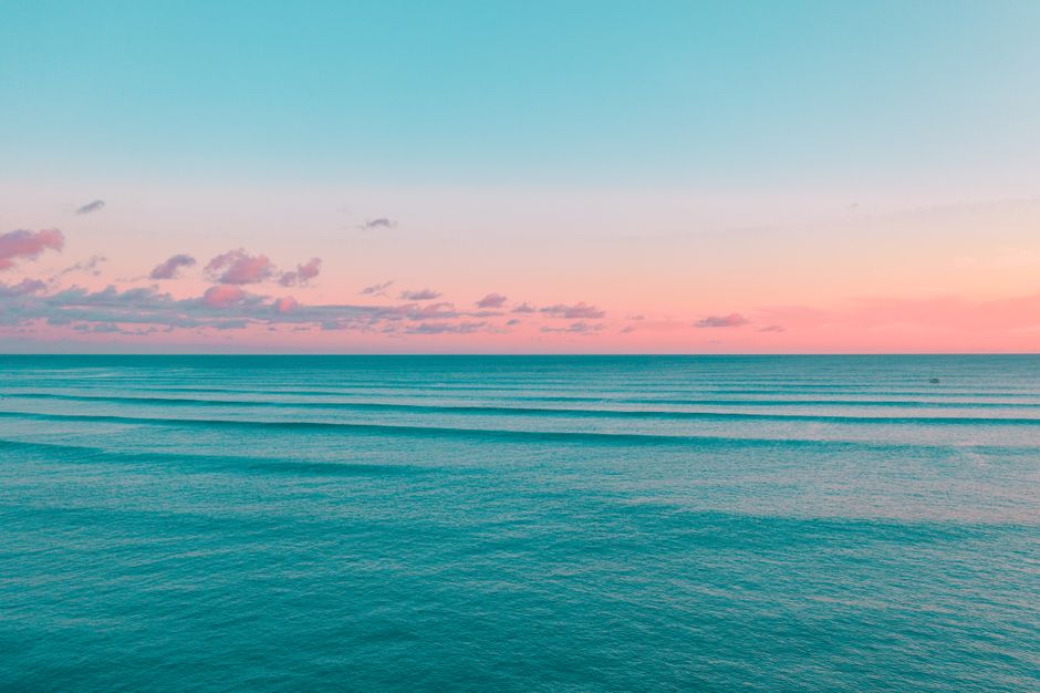 Peaceful ocean waves under a beautiful pink and blue sky during sunrise.