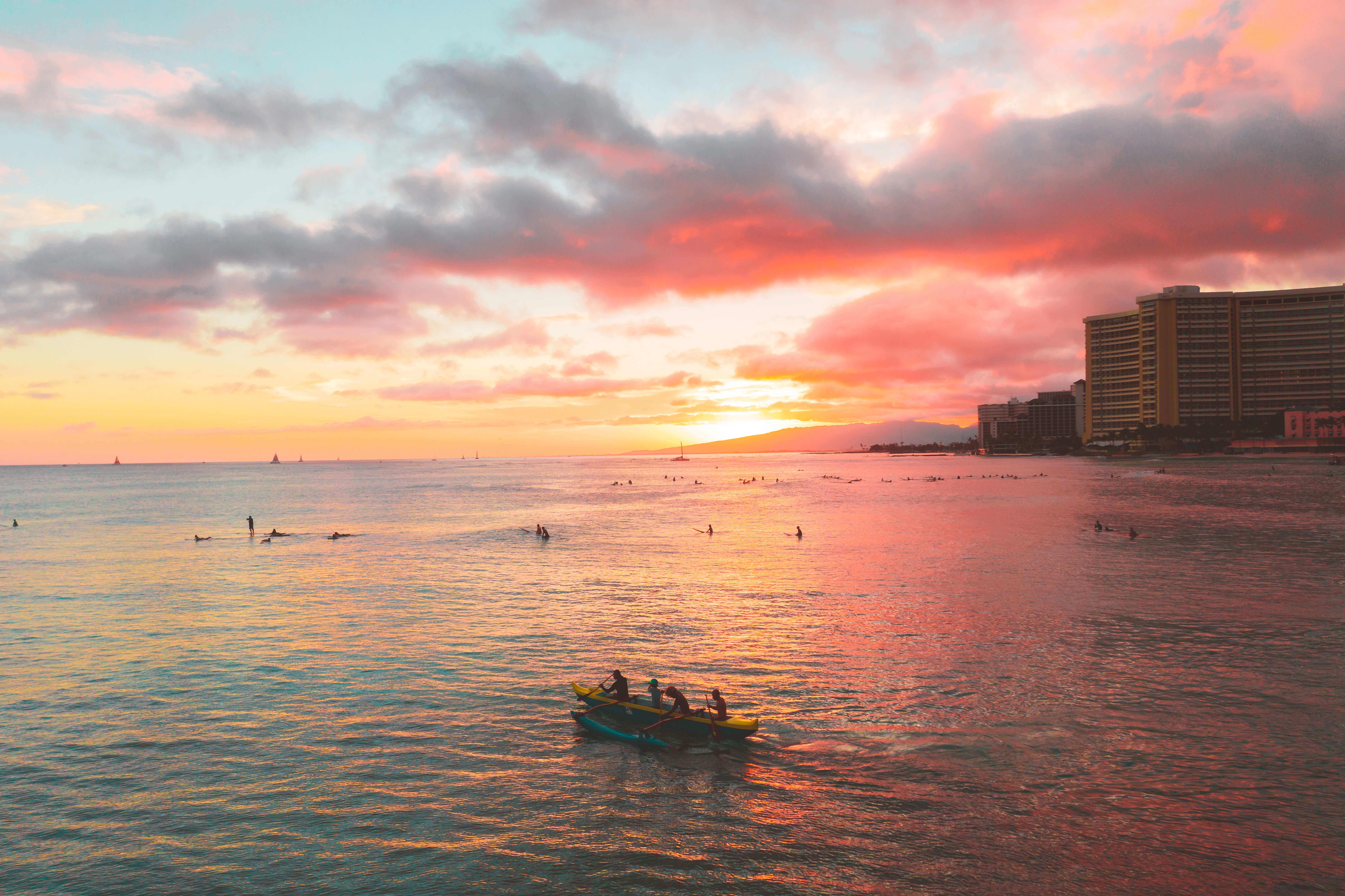 夕阳下的海面充满活力，小船与冲浪者共同构成一幅宁静的海景