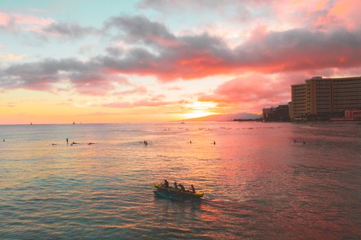 夕阳下的海面充满活力，小船与冲浪者共同构成一幅宁静的海景